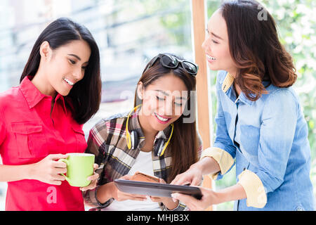 Three young women having fun while looking at a tablet PC during break Stock Photo