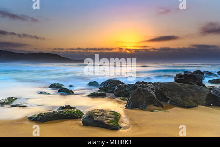Hazy Rocky Seascape - Capturing the sunrise from Killcare Beach on the Central Coast, NSW, Australia. Stock Photo
