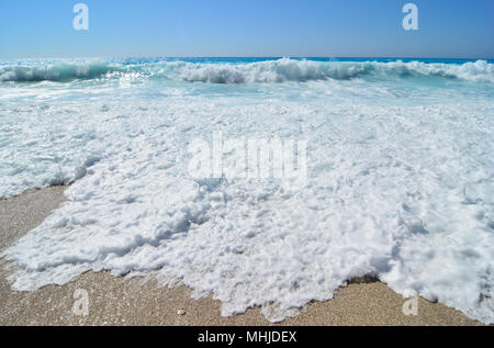 Powerful, big vawes and sea foam in foreground, white and bluue, colours of Greek flag, famous beach on Ionian Lefkada island Stock Photo