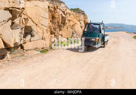 Man in typical italian three-wheeler Italian Piaggio Tricycle on the island of maddalena, this typ of car is still used a lot on Sardinia Stock Photo