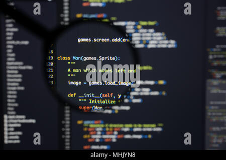 Real Python code developing screen. Programing workflow abstract algorithm concept. Lines of Python code visible under magnifying lens. Stock Photo