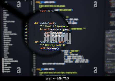Real Python code developing screen. Programing workflow abstract algorithm concept. Lines of Python code visible under magnifying lens. Stock Photo