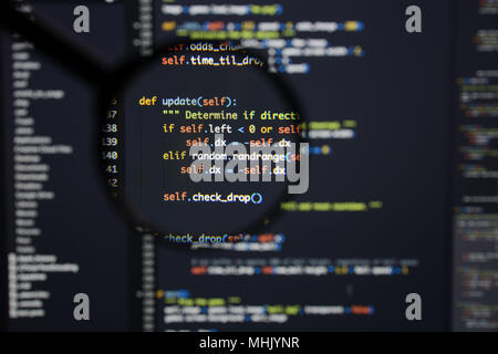 Real Python code developing screen. Programing workflow abstract algorithm concept. Lines of Python code visible under magnifying lens. Stock Photo