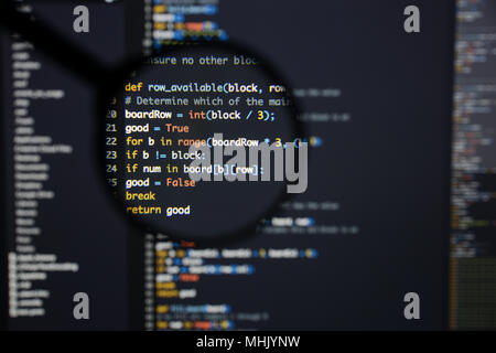 Real Python code developing screen. Programing workflow abstract algorithm concept. Lines of Python code visible under magnifying lens. Stock Photo