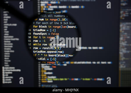 Real Python code developing screen. Programing workflow abstract algorithm concept. Lines of Python code visible under magnifying lens. Stock Photo