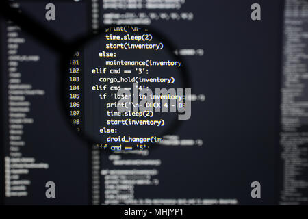 Real Python code developing screen. Programing workflow abstract algorithm concept. Lines of Python code visible under magnifying lens. Stock Photo