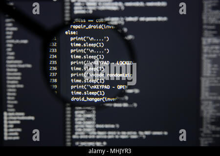 Real Python code developing screen. Programing workflow abstract algorithm concept. Lines of Python code visible under magnifying lens. Stock Photo