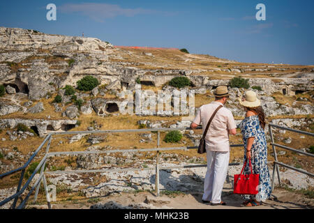 Matera (Italy), September 2017. Tourist looking at the ancient cave dwellings in front of the ancient town called 'Sassi' Landscape format. Stock Photo
