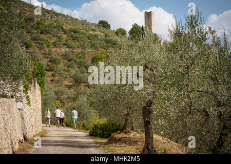 Pissignano (Italy), September 2017. People trekking on a trail on the Umbrian hills near the castle of Pissignano. Landscape format. Stock Photo
