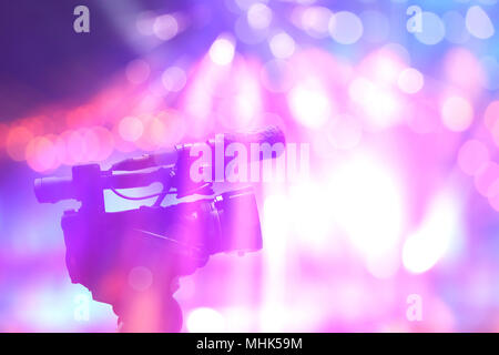 professional digital video camera in concert light on stage with colorful background Stock Photo