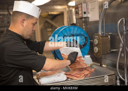 MEDITERRANEAN SEA (March 25, 2018) Marine Corps Staff Sgt. Salvatore Dely, from Tucson, Az., assigned to the Battalion Landing Team, 26th Marine Expeditionary Unit, places bacon on a sheet pan in preparation for brunch aboard the San Antonio-class amphibious transport dock ship USS New York (LPD 21) March 25, 2018. New York, homeported in Mayport, Fla., is conducting naval operations in the U.S. 6th Fleet area of operations. (U.S. Navy Stock Photo