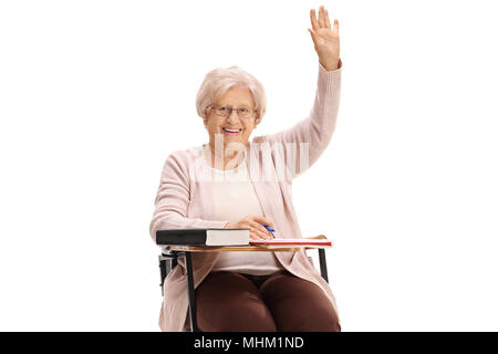 Mature woman holding her hand up sitting in a school chair isolated on white background Stock Photo