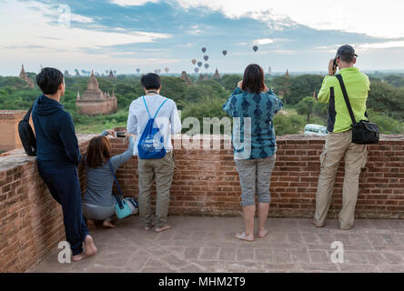 Tourists take photos of hot-air balloons over temples of Bagan, Shwe Nan Yin Taw Monastic Complex, Myanmar (Burma) Stock Photo