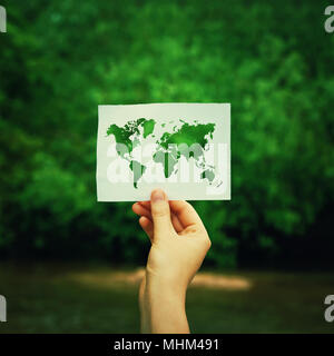 Woman hand holding a paper sheet with the world map over green forest nature background. Ecology and greening concept, global environmental issues wor Stock Photo
