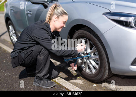 A woman mechanic loosening nuts on a wheel for a tire change Stock Photo