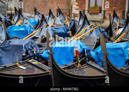 A group of gondolas, covered in blue tarpaulin, parked in a canal basin near St Mark's Square, Venice Stock Photo