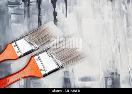 Two paint brushes on artistic canvas with black and white brush strokes. Stock Photo