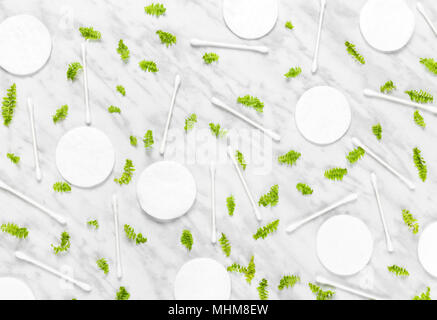 Cotton pads, Q-tips and green leaves on marble background. Flat lay composition. Stock Photo