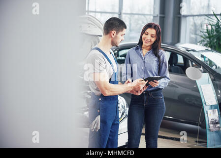 A man mechanic and woman customer discussing repairs done to her vehicle Stock Photo