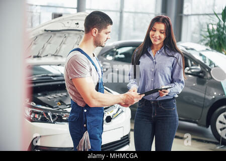A man mechanic and woman customer discussing repairs done to her vehicle Stock Photo