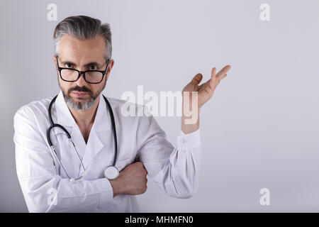 Middle age doctor wearing eyeglasses , pointing or holding something with his hand Stock Photo