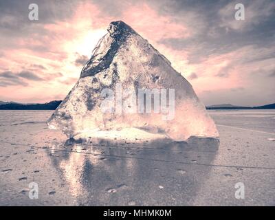 Beautiful epic ice crystal in the frozen bay.  Sun rays reflection in cracks, backlight  of the setting sun. Stock Photo