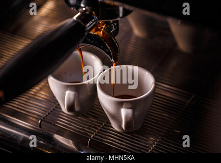 Professional espresso machine pouring strong looking fresh coffee into a ceramic cup Stock Photo