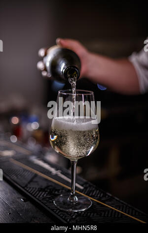 Barmann pours champagne in wineglass on the bar counter Stock Photo