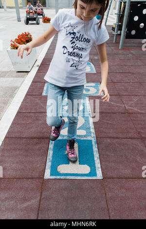 Girl in sneakers playing hopscotch, board in a playground Stock Photo