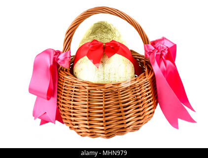 Wrapped chocolate easter egg with bow ina wicker basket Stock Photo