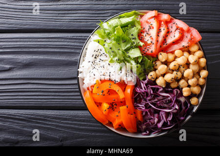 Delicious healthy buddha bowl with fresh vegetables, chickpeas and rice close-up on the table. horizontal top view from above Stock Photo