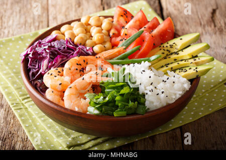 Freshly prepared Buddha bowl with prawns, vegetables, chickpeas, rice and greens close-up on the table. horizontal Stock Photo