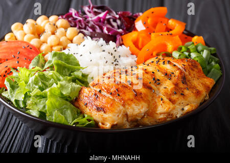 Salad Buddha bowl with chicken grilled, vegetables, chickpeas, rice and lettuce close-up on the table. horizontal Stock Photo