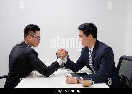 Two businessmen competing arm wrestling in office Stock Photo