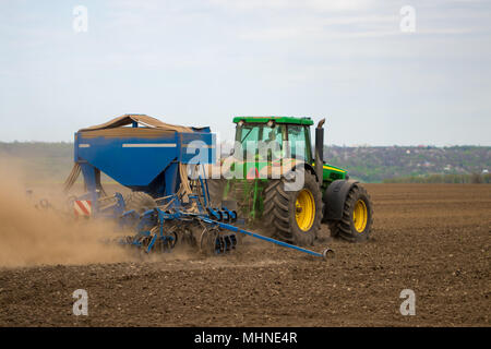 Farmer in tractor preparing land with seedbed cultivator as part of pre seeding activities in early spring season of agricultural works at farmlands. Stock Photo