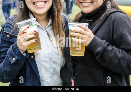 Girls smiling with beer in hand at an event Stock Photo