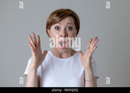 Close up portrait of a beautiful young red haired caucasian woman with a surprised face. Attractive female looking amazed with wide eyes and mouth ope Stock Photo