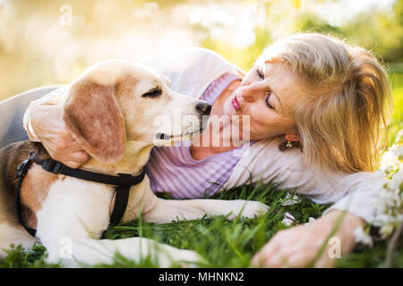 Beautiful senior woman with dog in spring nature. Stock Photo