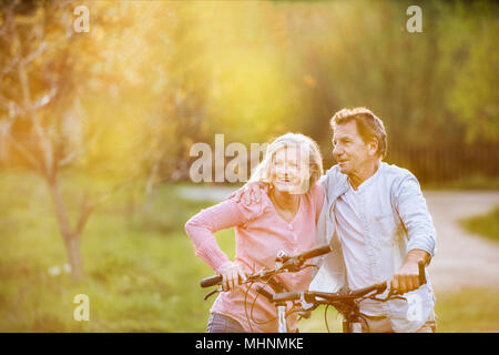 Beautiful senior couple with bicycles outside in spring nature. Stock Photo