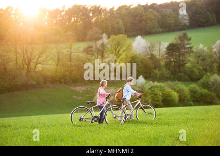 Beautiful senior couple with bicycles outside in spring nature. Stock Photo