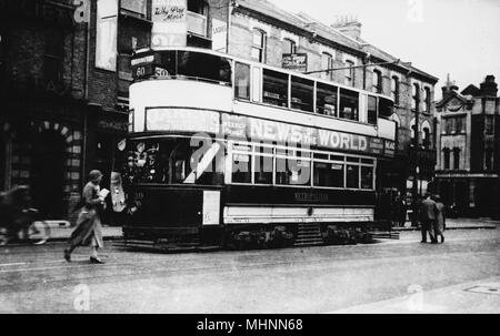 Harrow Road tram on Route 60 going to Paddington, advertising The News of the World newspaper.      Date: circa 1920s Stock Photo