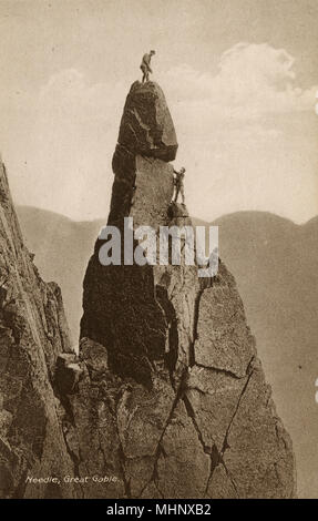 Napes Needle, Great Gable, Keswick, Lake District, with a climber standing on the summit and two others below him.      Date: circa 1920 Stock Photo