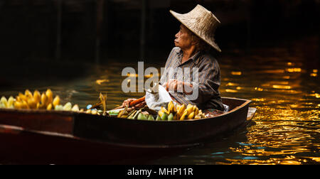 Ratchaburi, Thailand - April 28, 2018: fruit gardener, merchant trader is rowing boat to sell produce to tourists at Damnoen Saduak Floating Market, o Stock Photo
