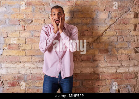 Portrait of a surprised handsome young man in a pink shirt. Stock Photo