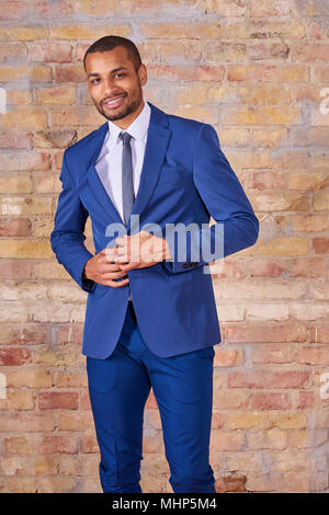 Portrait of a happy young businessman buttoning his suit. Stock Photo