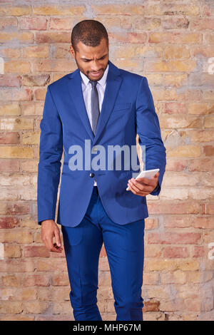 A serious handsome young businessman using his smartphone in a suit. Stock Photo