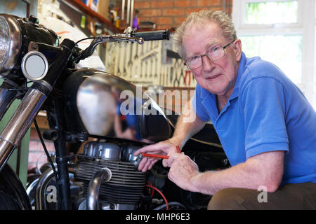 Portrait Of Senior Man Working On Vintage Motorcycle In Garage Stock Photo