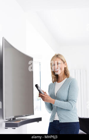 Portrait Of Mature Woman With New Curved Screen Television At Home Portrait Of Mature Woman With New Curved Screen Television At Home