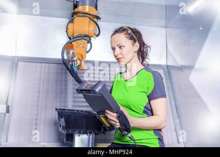 A young female technician while machine constructing in a manufacturing plant Stock Photo