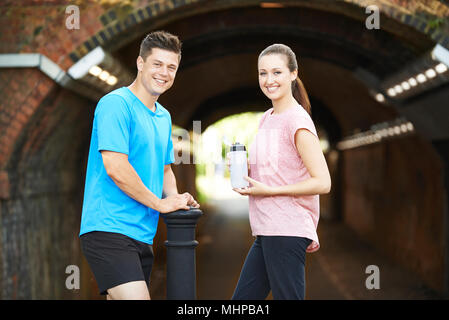 Portrait Of Couple Taking A Break During Exercise In Urban Environment Stock Photo